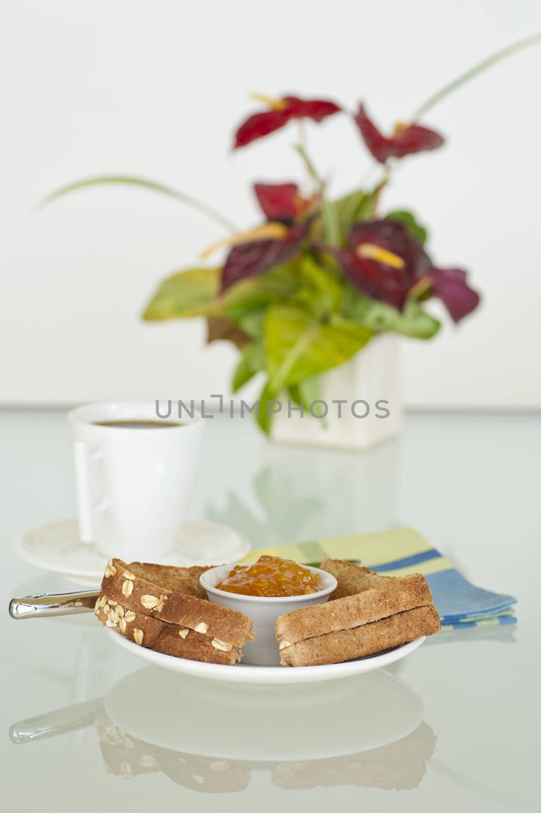 Breakfast consisting of toast with orange marmalade and coffee.