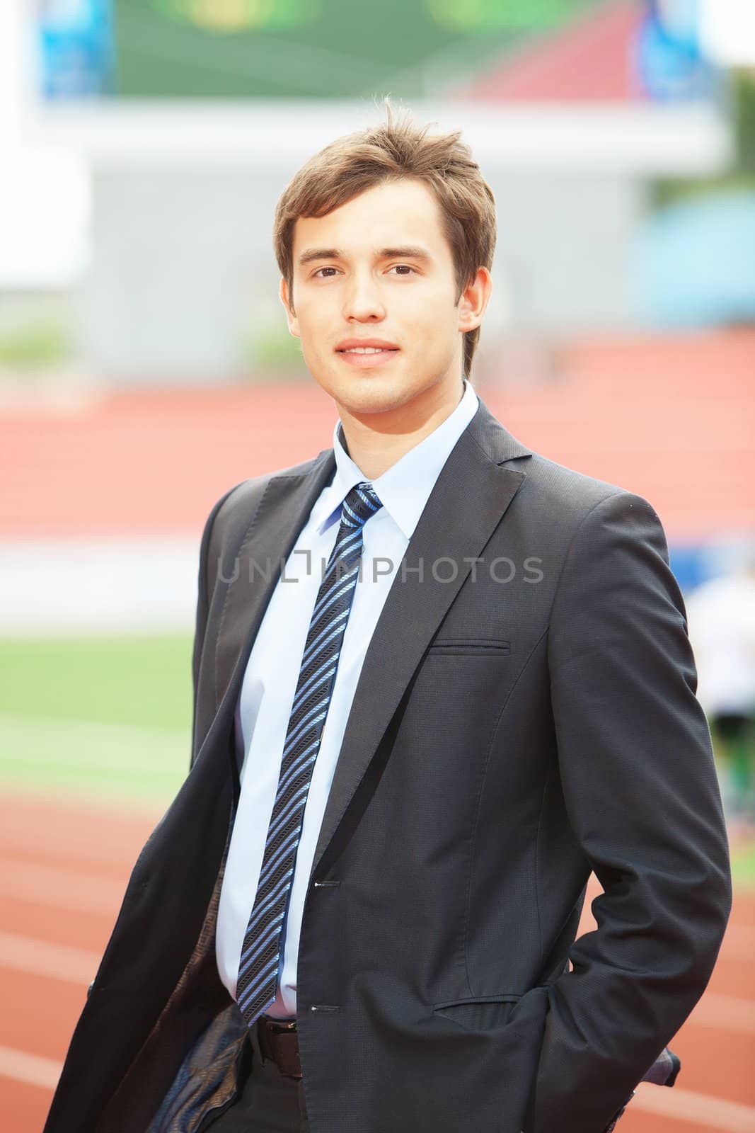 Satisfied smiling businessman standing in the summer outdoors.