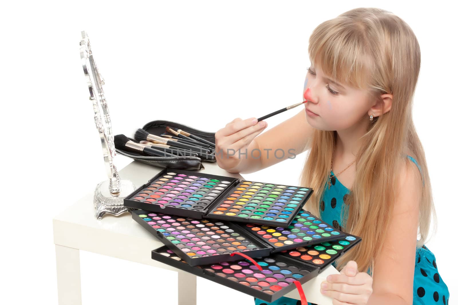 Little girl paints his face makeup, on white background