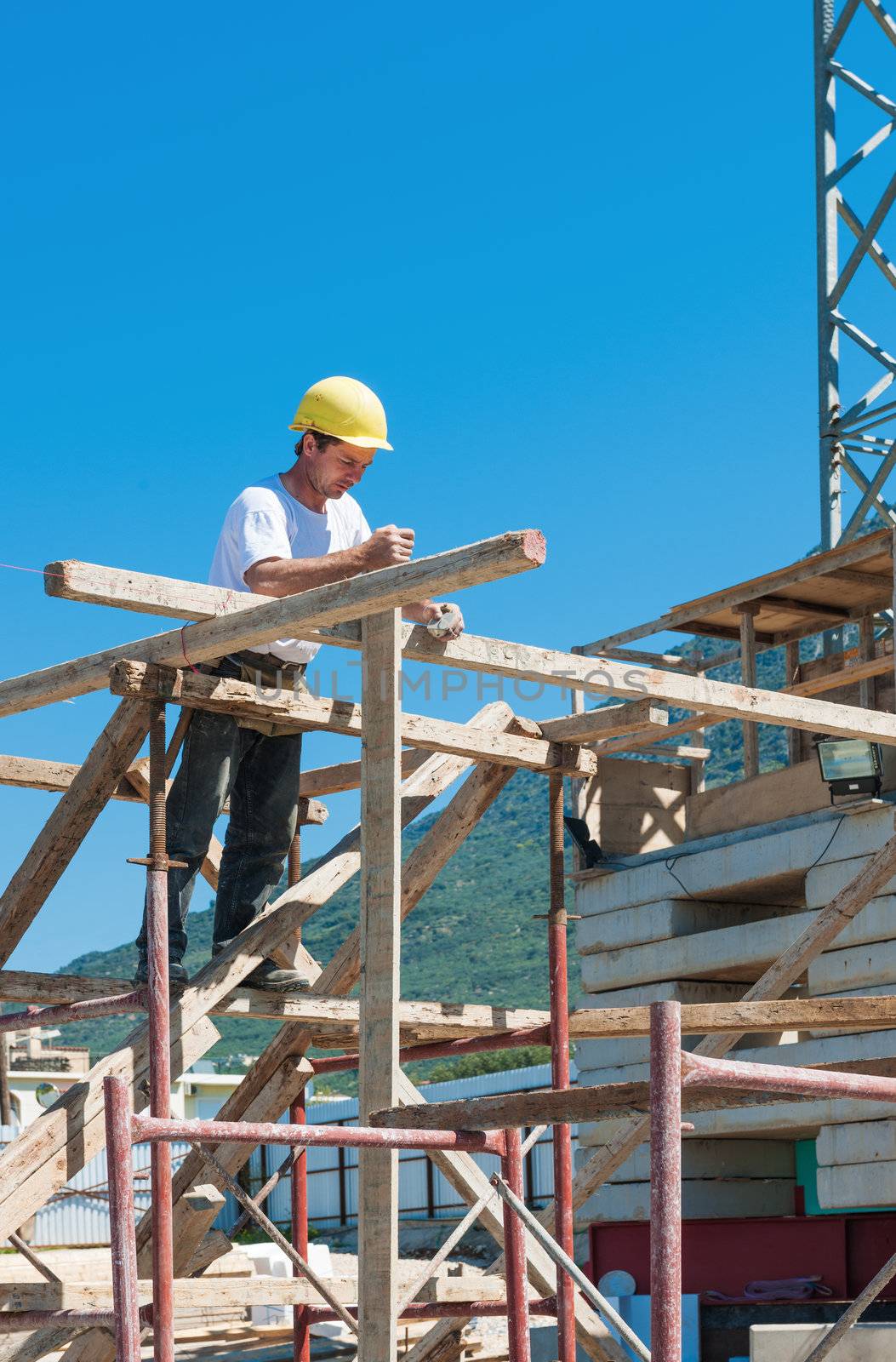 Construction worker on scaffold busy with guiding strings