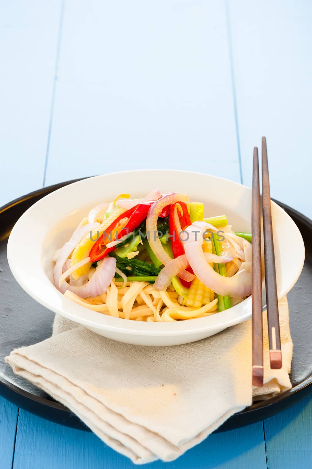 spicy vegetarian noodle in a white plate and light blue wooden table