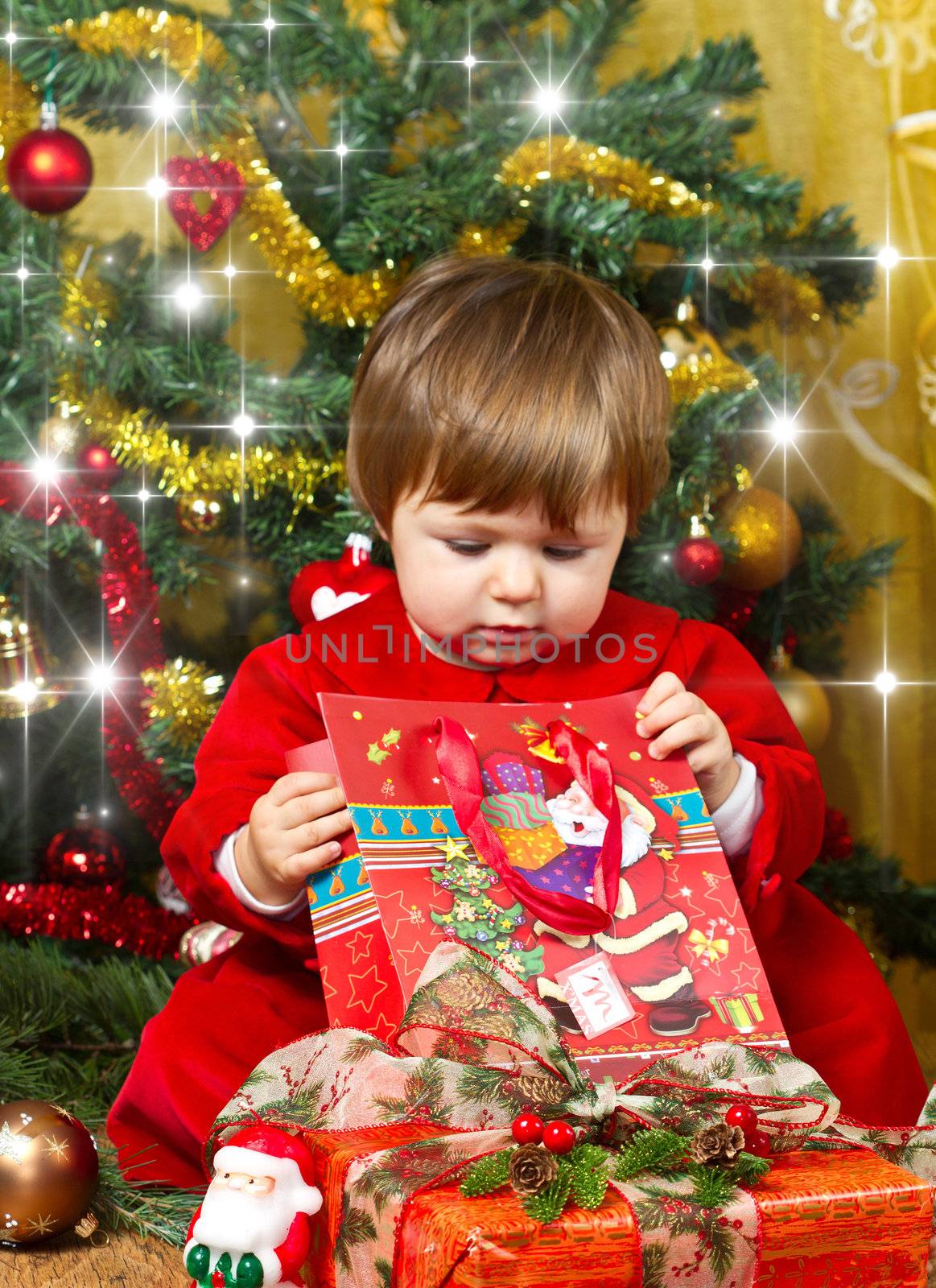 baby play with present box at Christmas tree by lsantilli