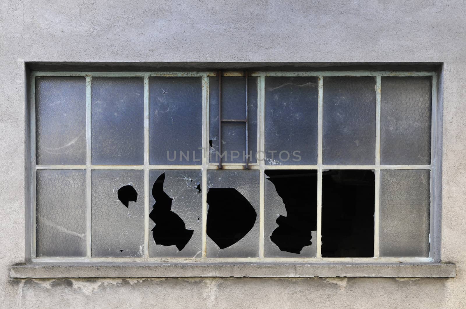 Old industrial windows with broken glasses in a concrete wall