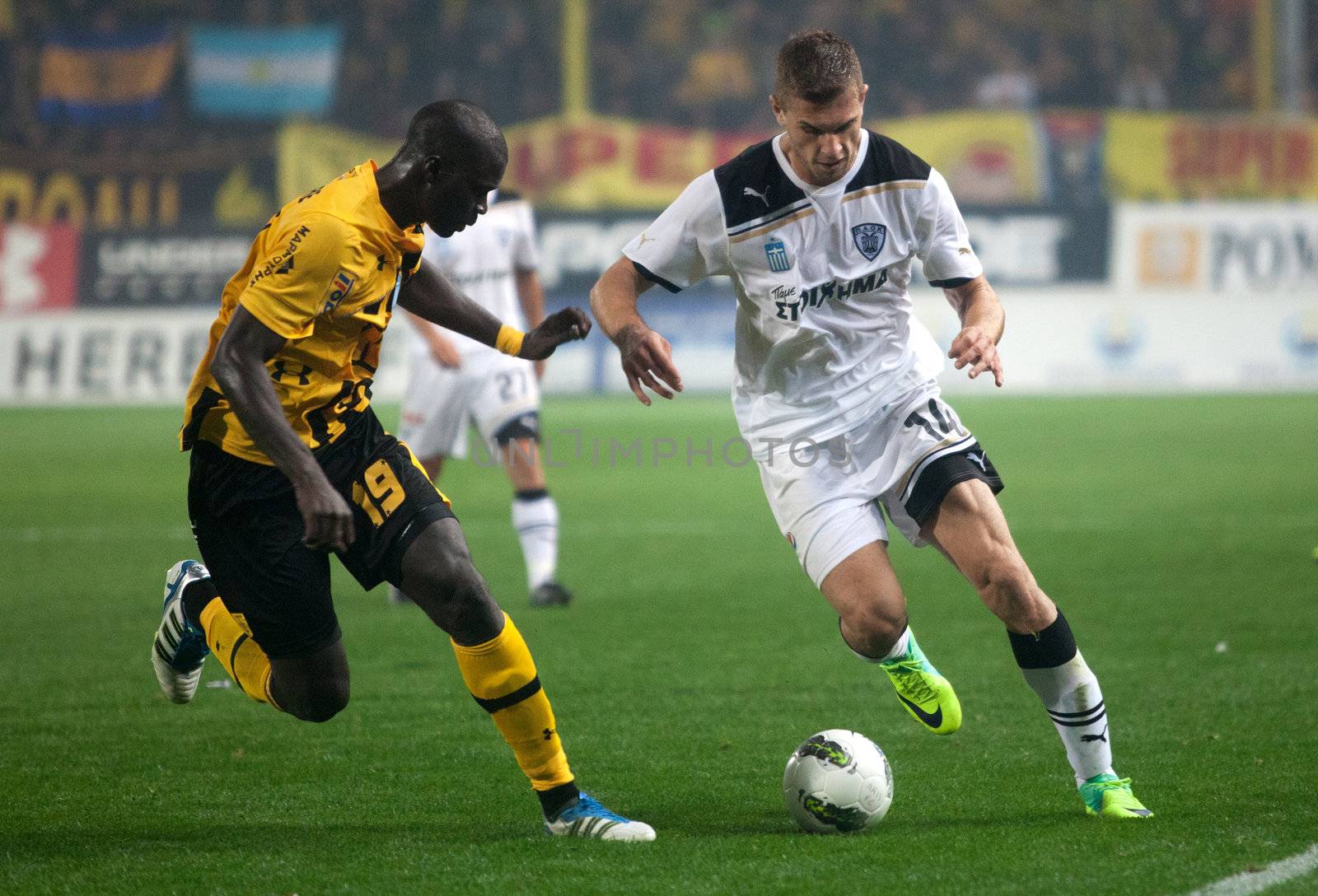 Claiming the ball between players of football teams Paok and Ari by Portokalis