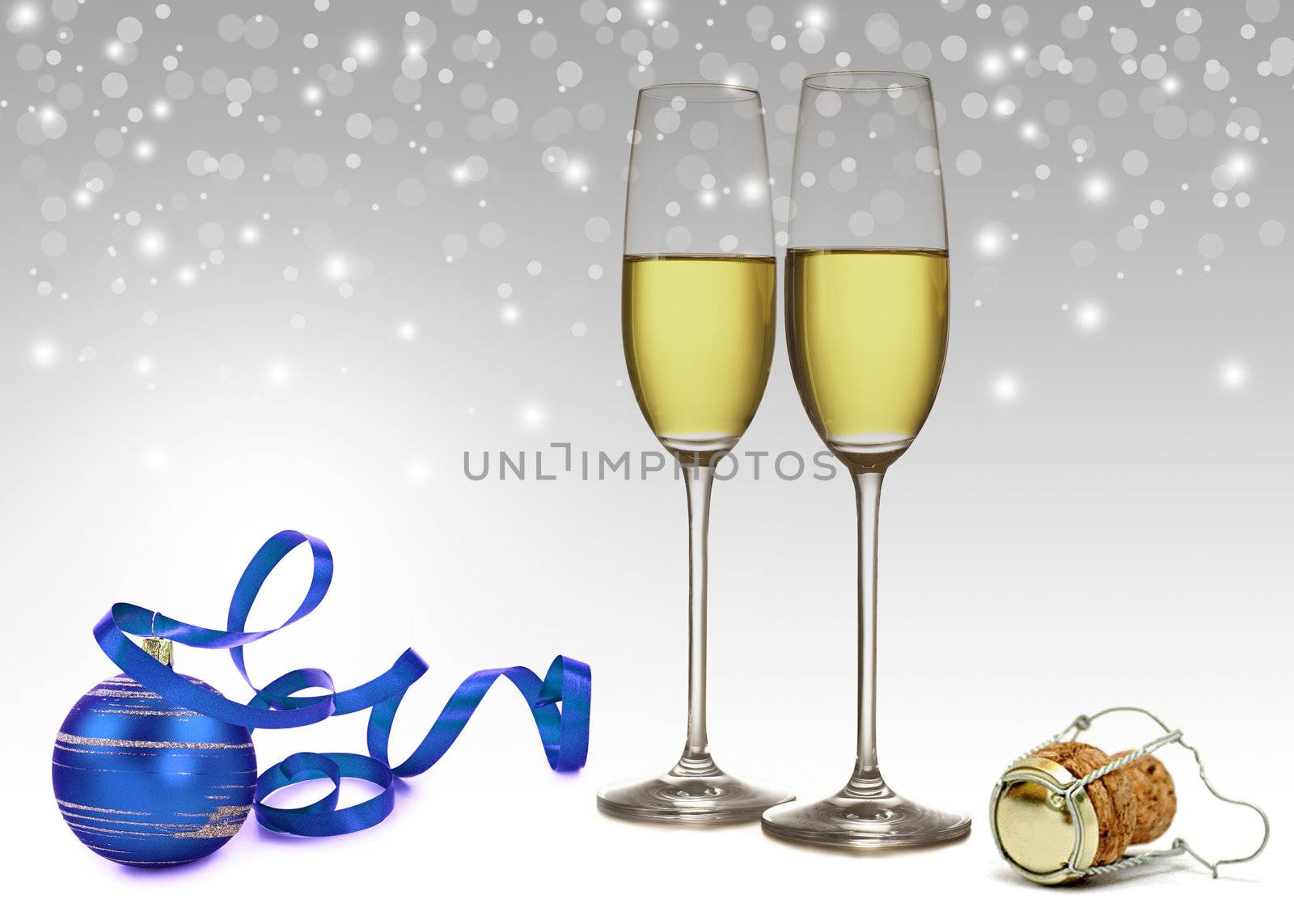 Seasonal greetings: a blue Christmas tree ornament with ribbon, 2 champagne glasses and a champagne cork on a light and
elegant white-grey bokeh background.