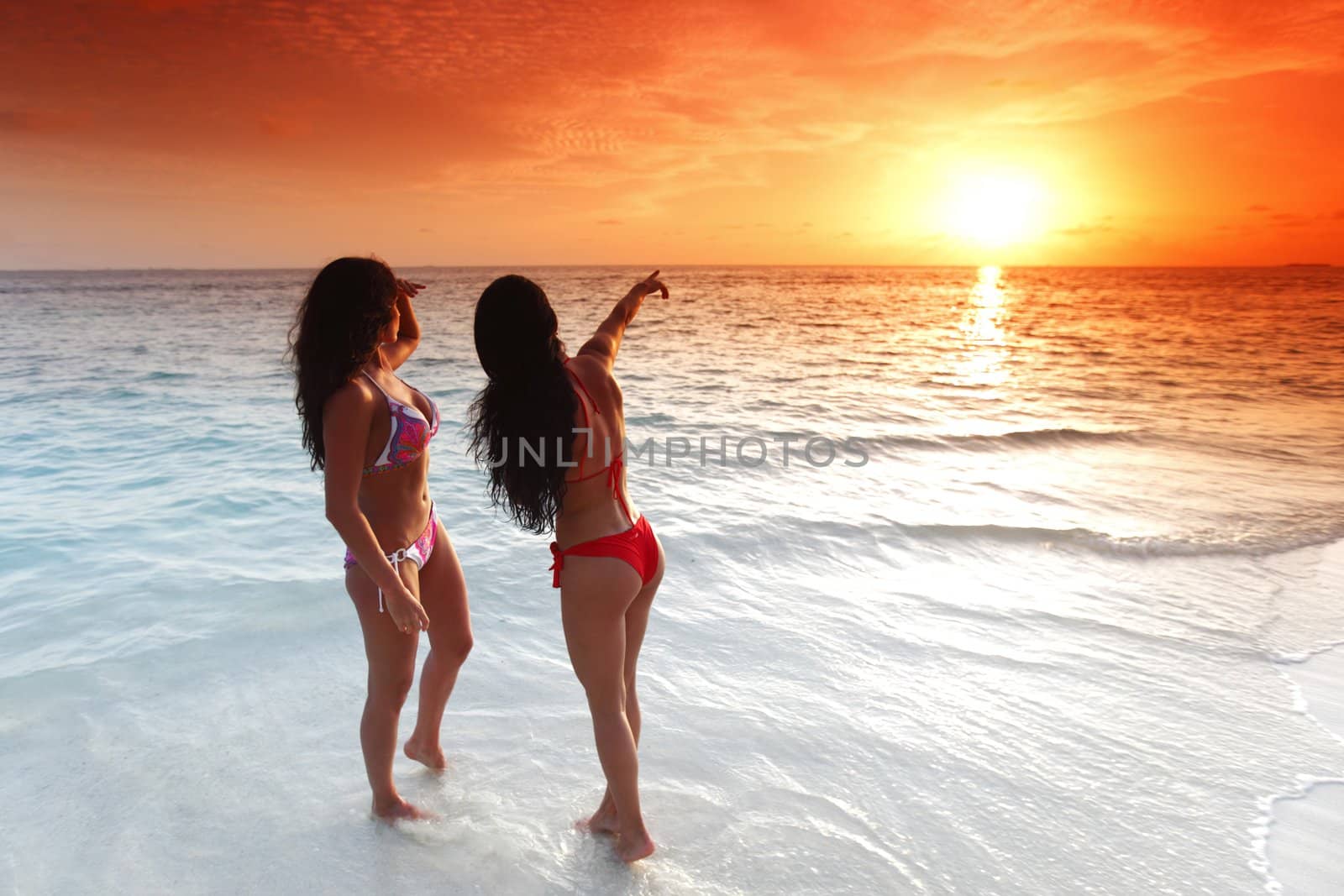 Two women enjoying sunset on beach by Yellowj