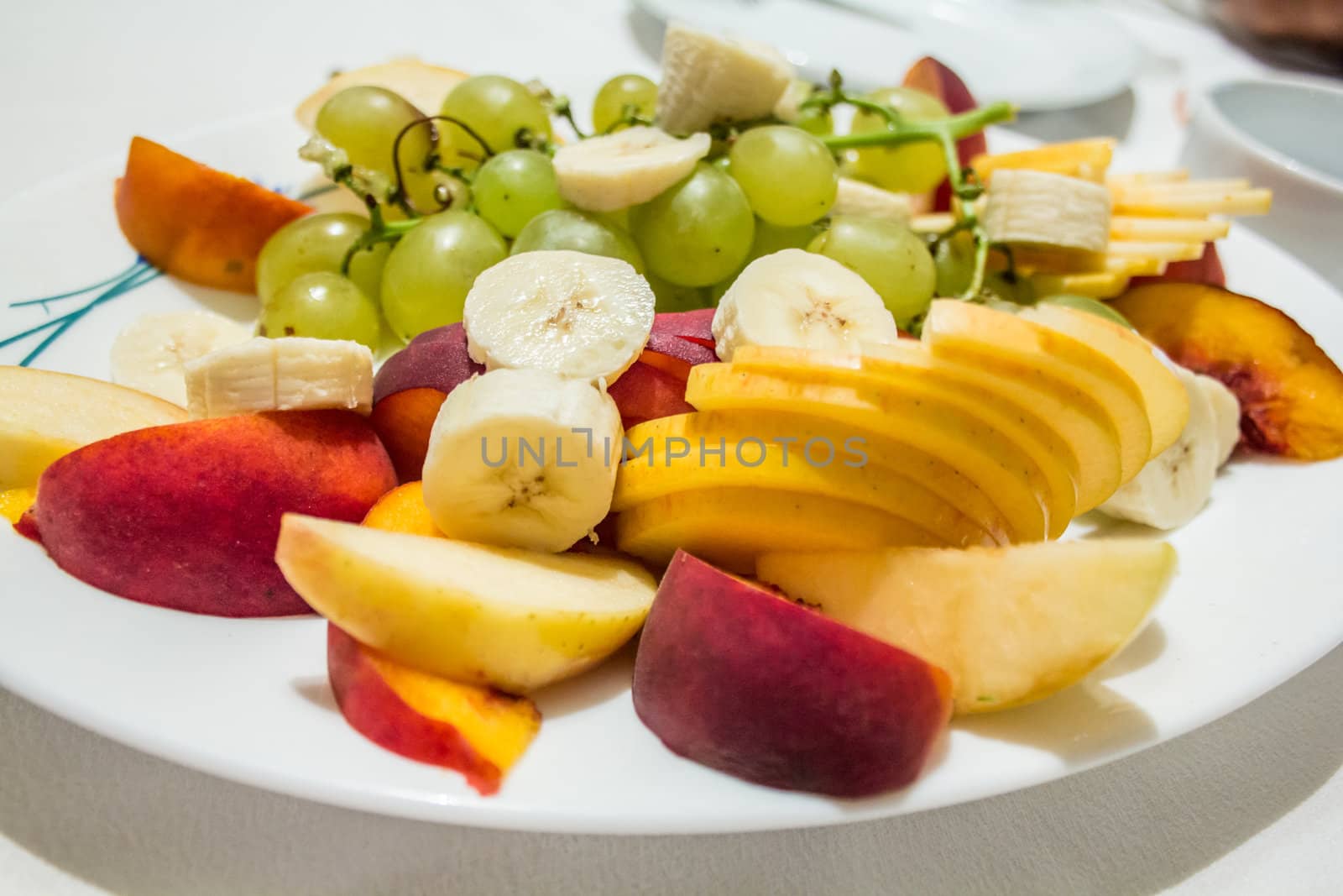 A plate filled with ripe and tasty peaches, banana and grapes