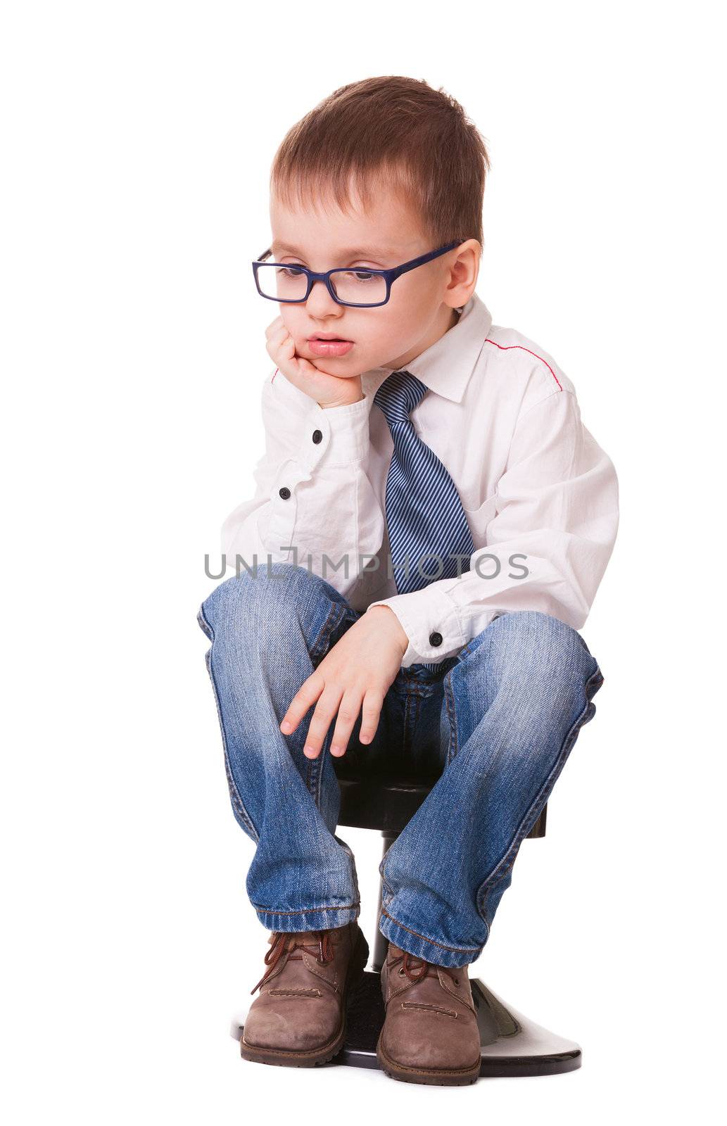 Very sad clever kid in jeans and shirt sitting on small chair isolated on white background