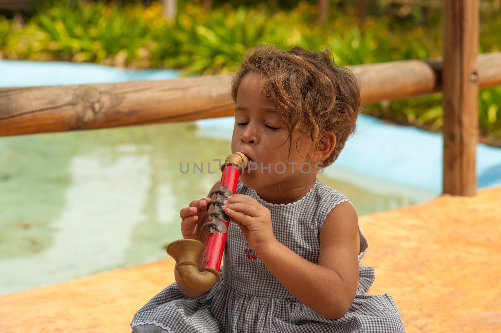 Cute Hispanic girl playing with a toy saxophone