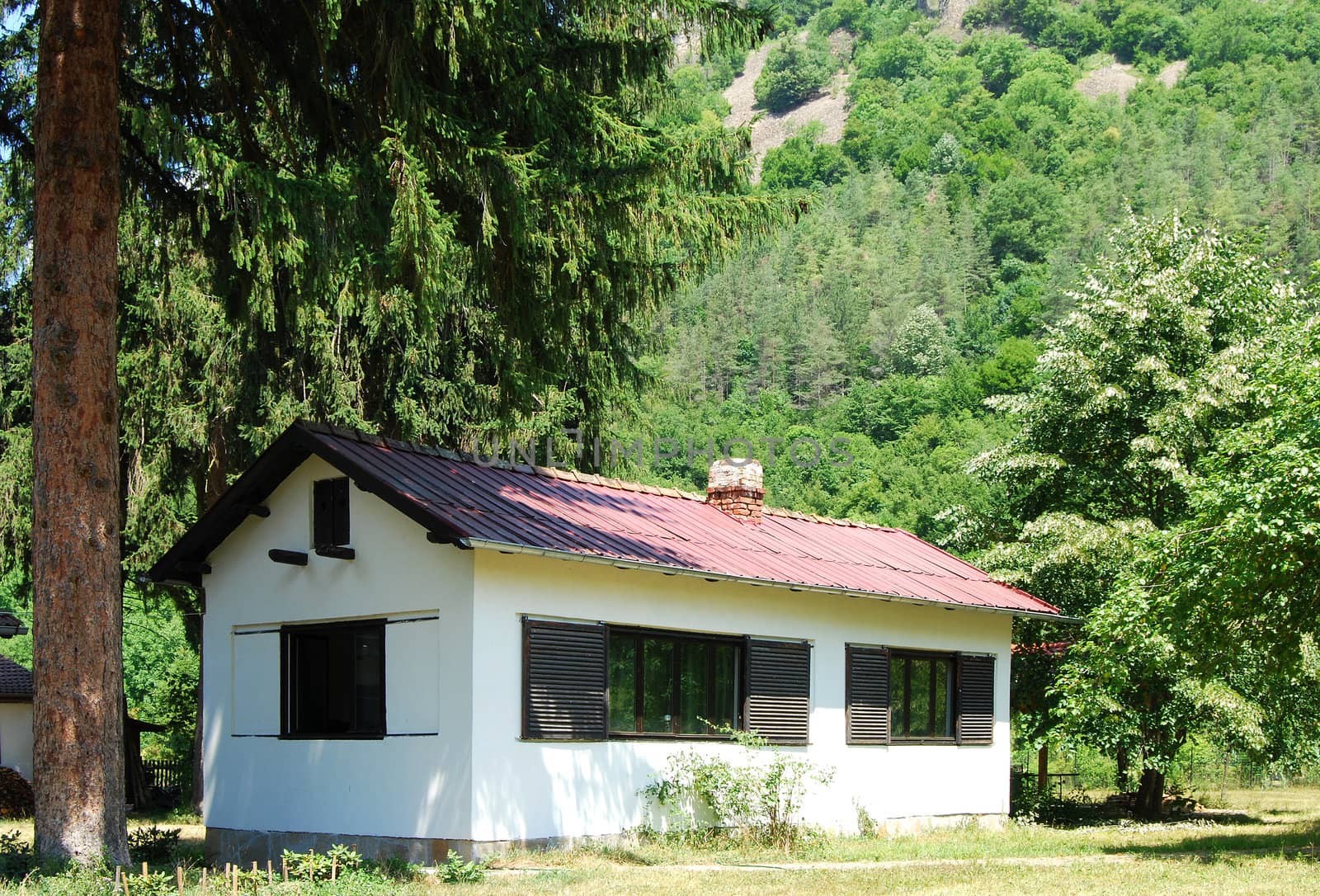 White country house in mountain valley in summer
