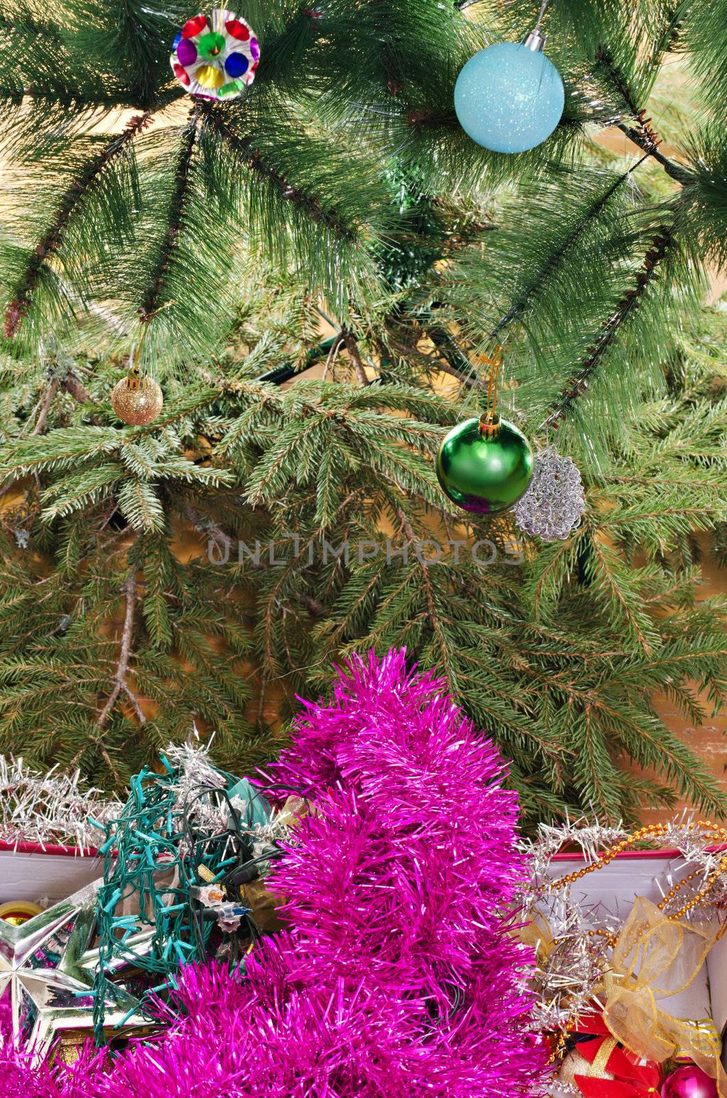 Detail of box with Christmas decorations in front of pine tree with baubles