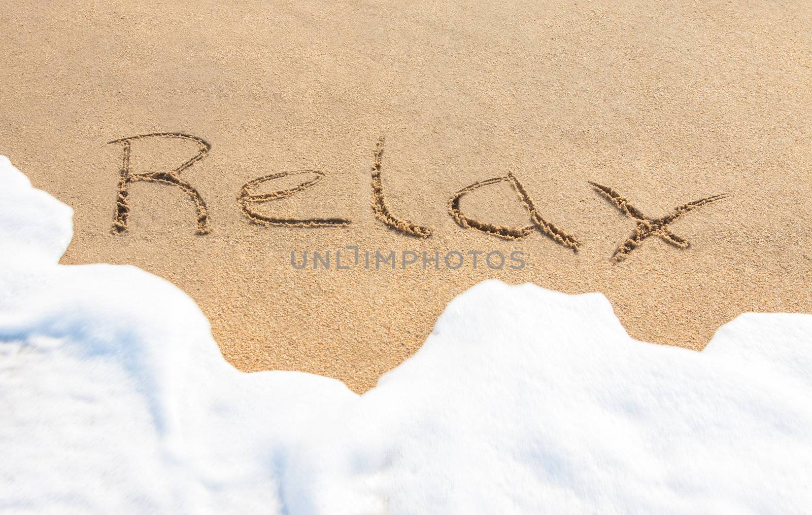 Relax - written in the sand with a foamy wave underneath