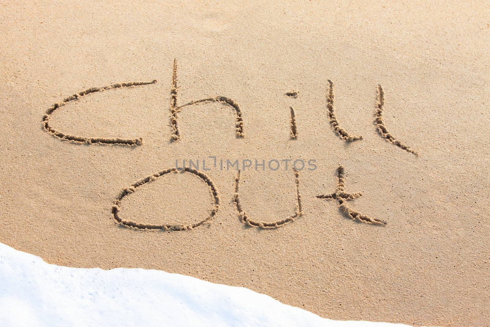 Chill out - written in the sand with a foamy wave underneath
