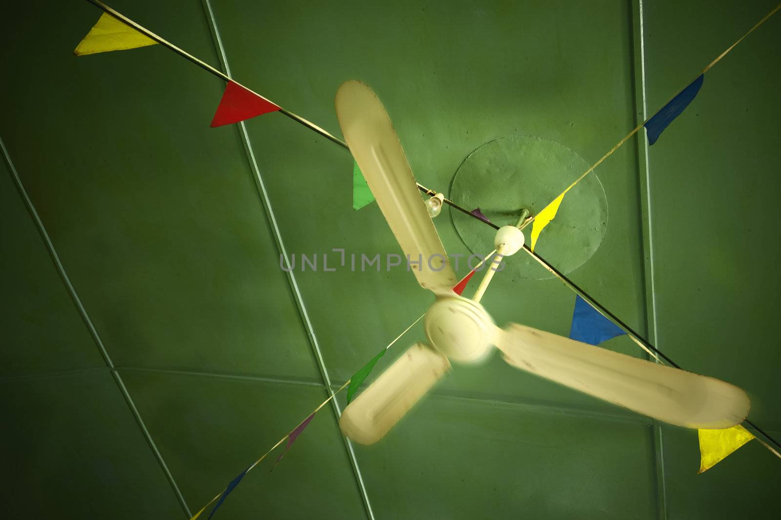 Old ceiling fan spinning in a cafe ceiling decorated with colorful bunting