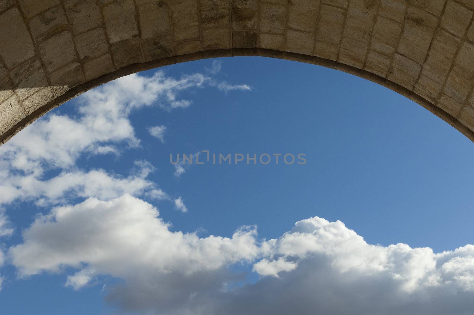 View of the sky with clouds through an old stone archway