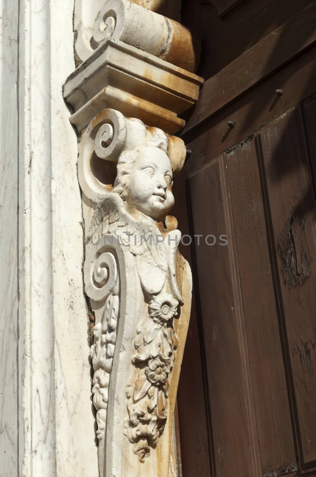 A baroque angel caryatid carved in marble on a door threshold, Portugal