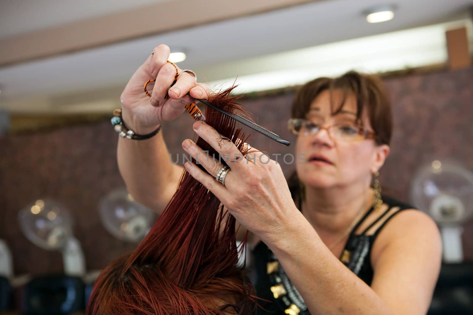 A young woman getting her hair cut by a professional hairdresser at a salon.  Shallow depth of field.