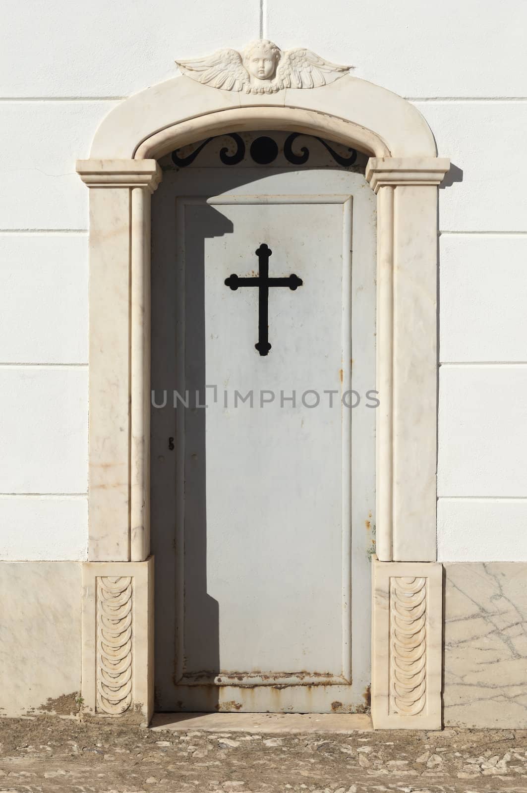 Door of a tomb in marble stonework topped by a carved angel, Portugal