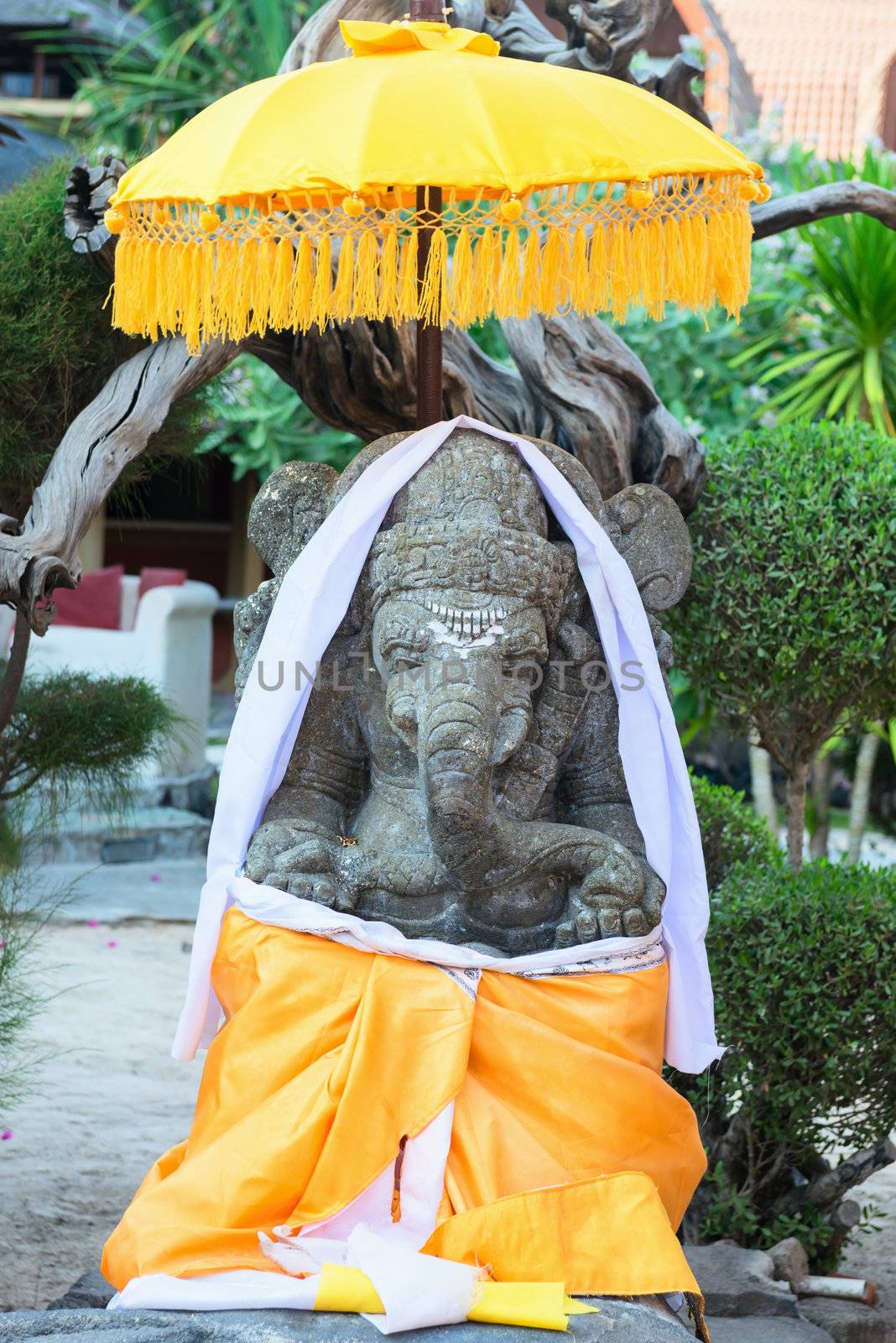 Ganesh sculpture decorated with yellow fabric and umbrella in Bali style
