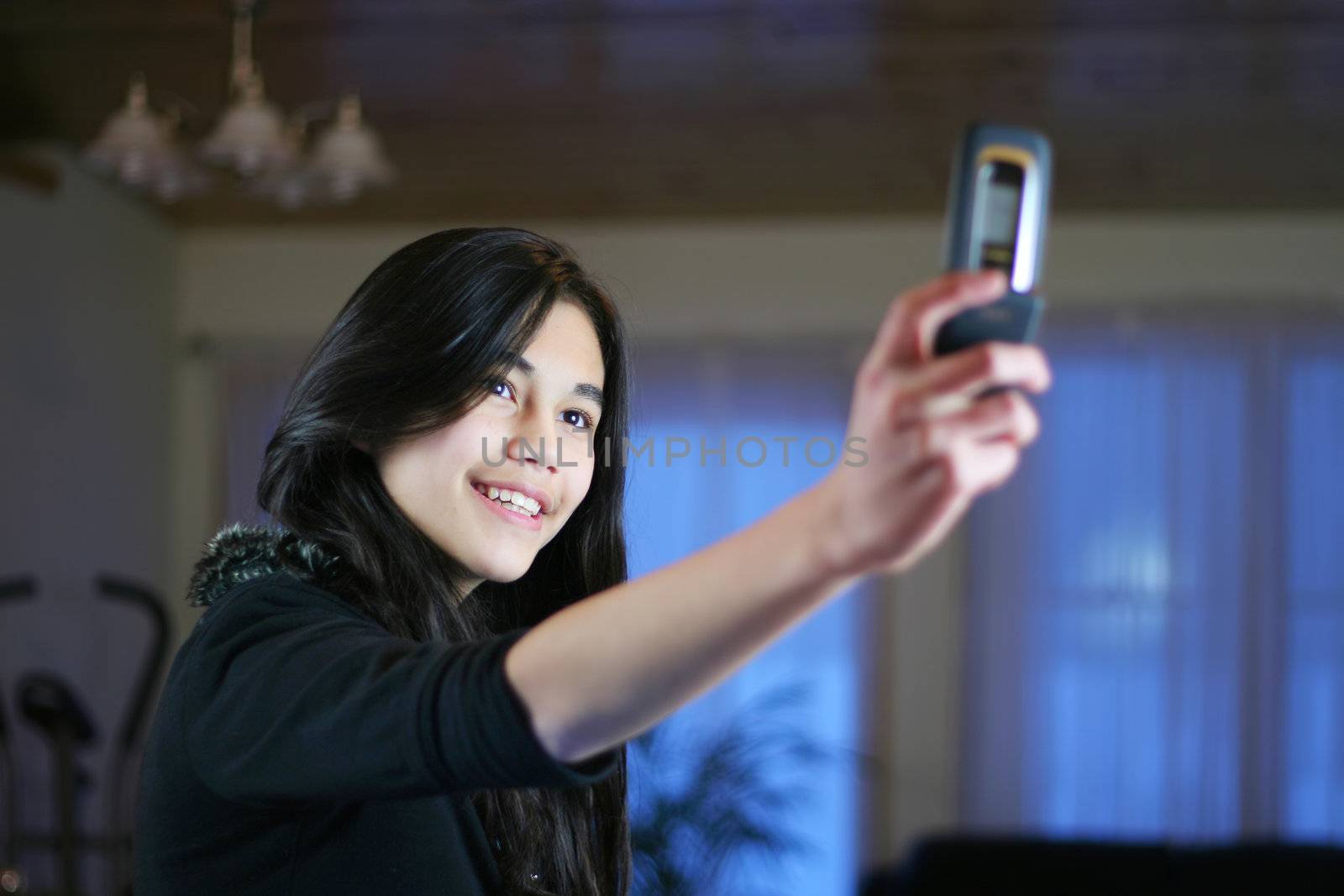 Young teen girl taking her own picture with camera phone.