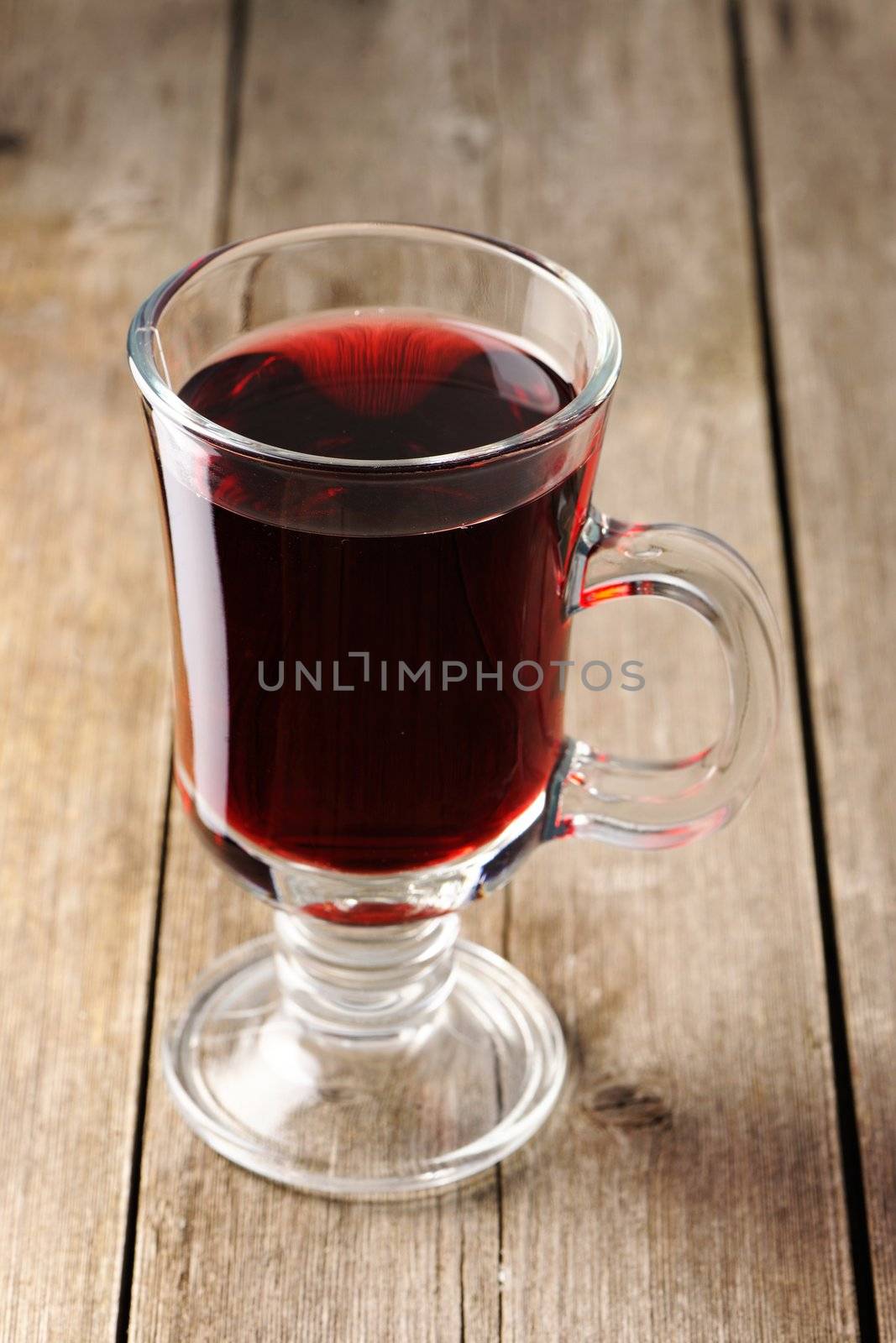 Glass of red mulled wine on wooden table