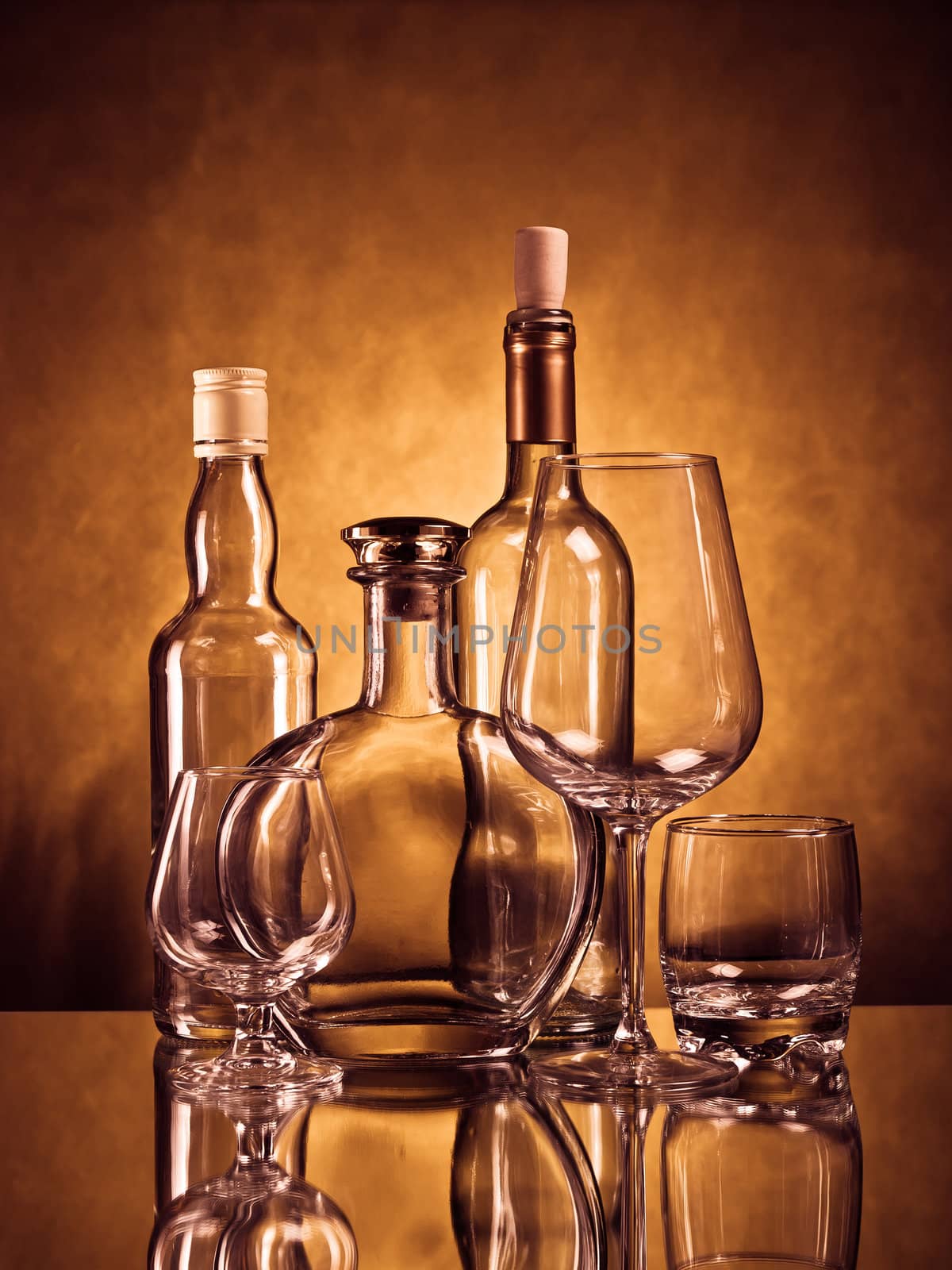 Whiskey, cognac and wine bottles with glasses on brown grunge background