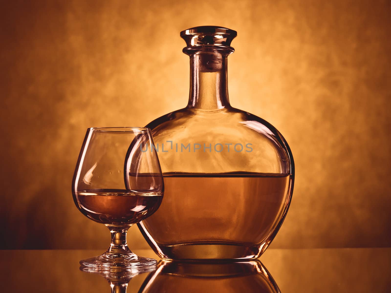 Round elegant bottle of cognac with a filled glass 
