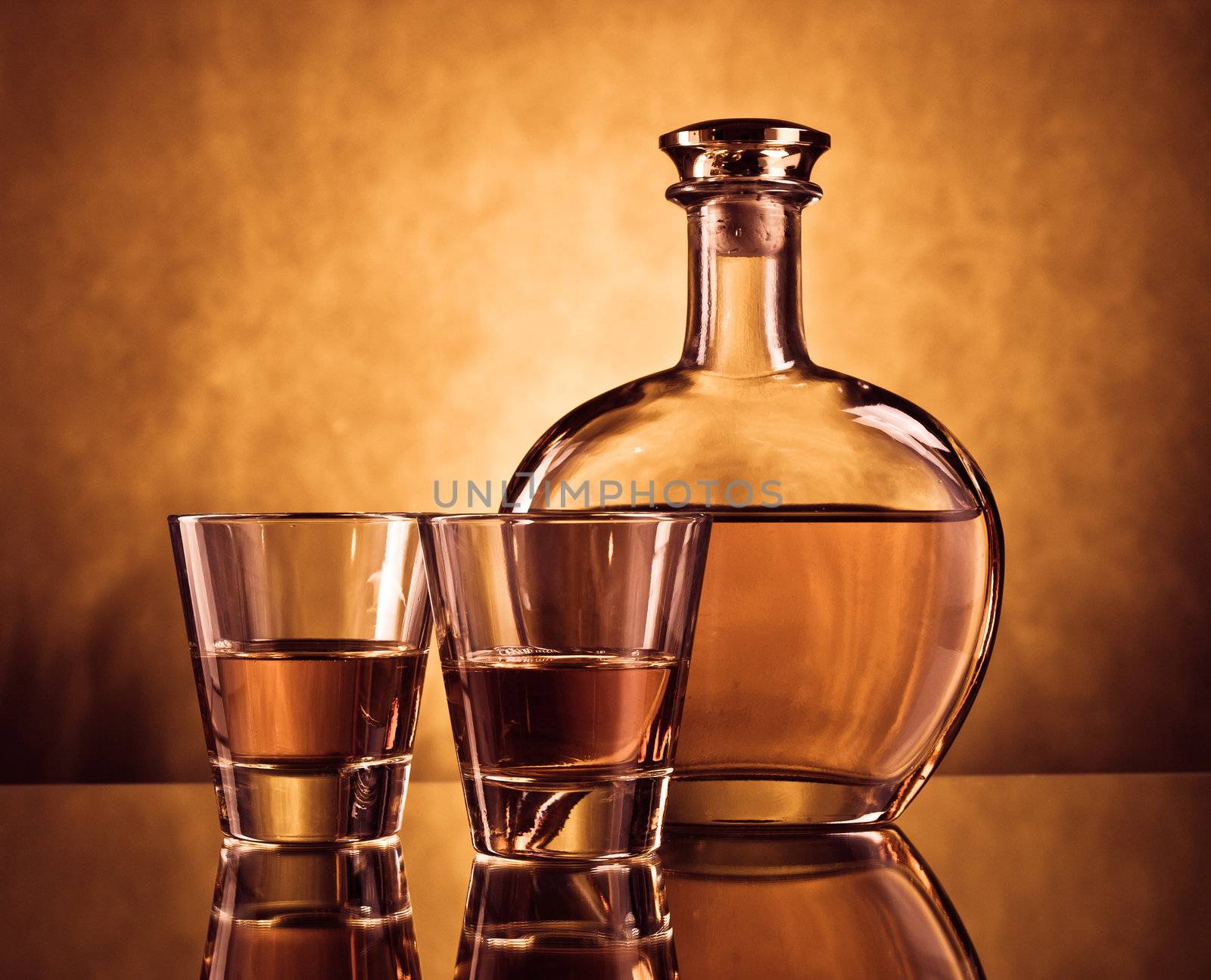 Elegant round bottle of alcohol with two glasses