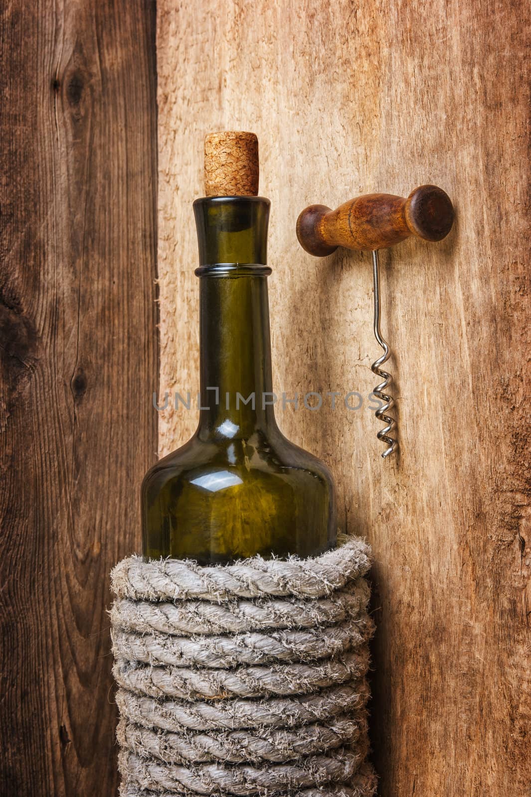 bottle of wine wrapped with rope on the background of the old wooden planks