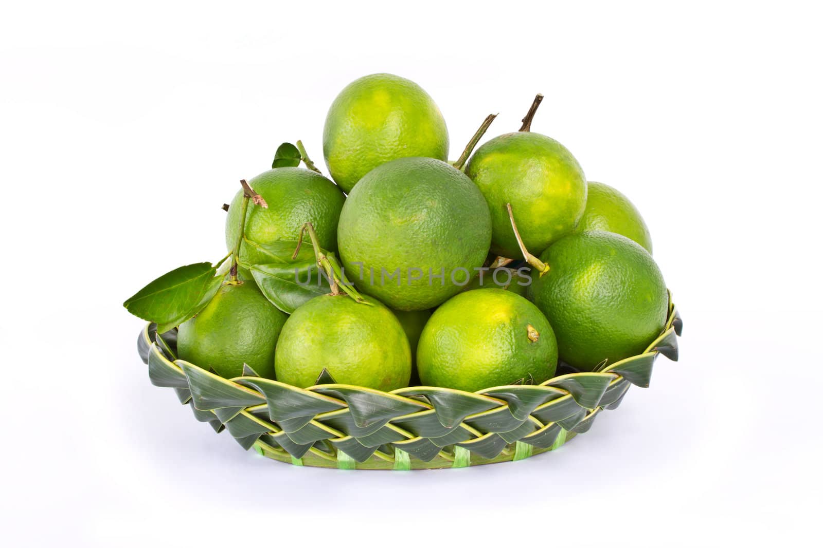 Green sweet oranges in coconut leaf basket on white background