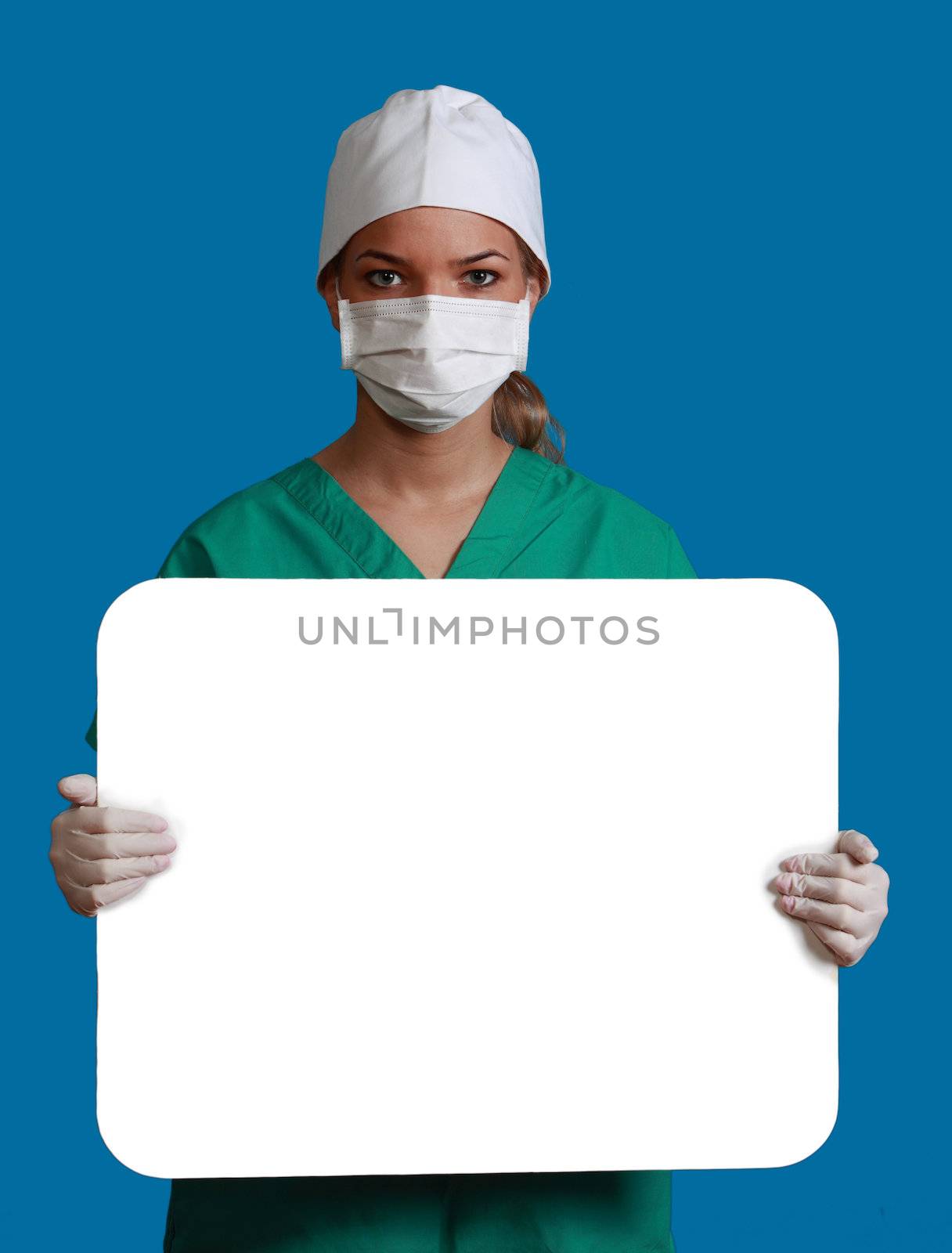 A young woman doctor in a mask holding an empty bill board against a blue background.
