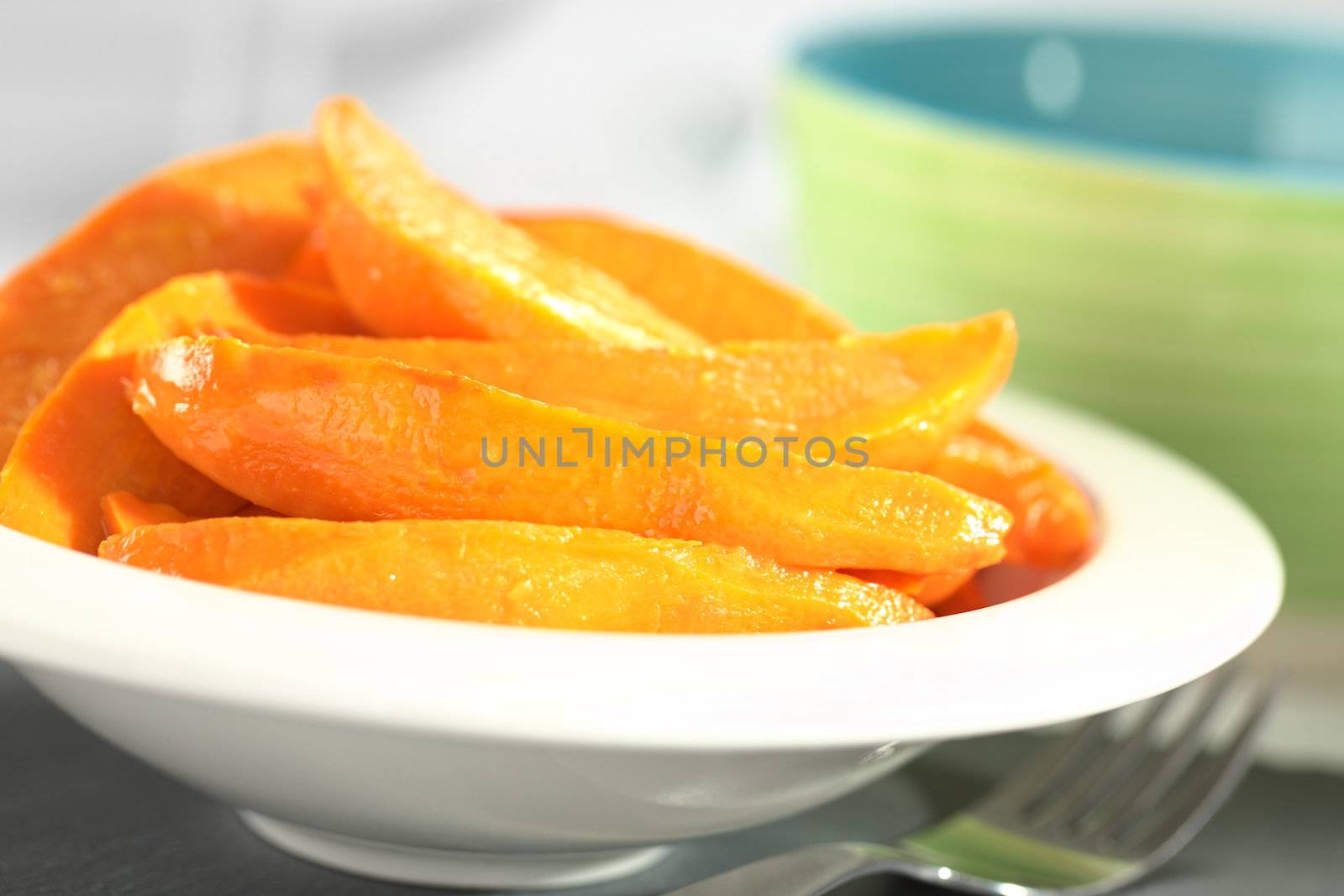 Fresh homemade caramelized sweet potato wedges in white bowl (Selective Focus, Focus one third into the sweet potatoes)