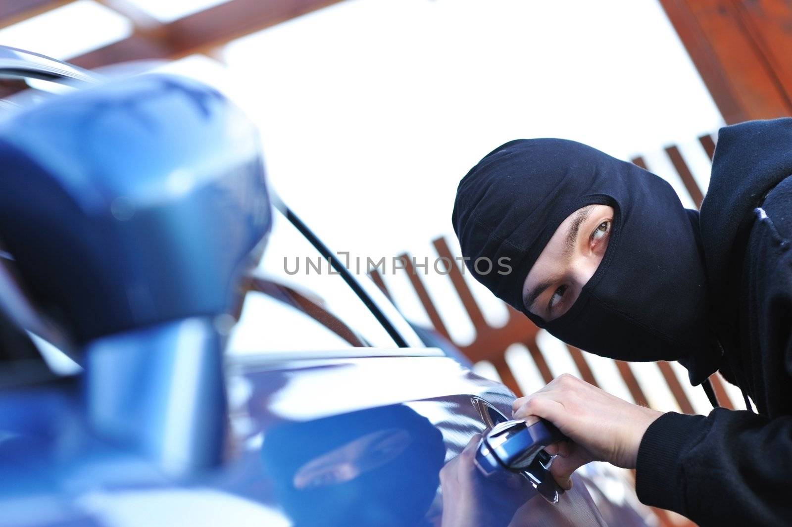 Young man in mask trying to steal a car