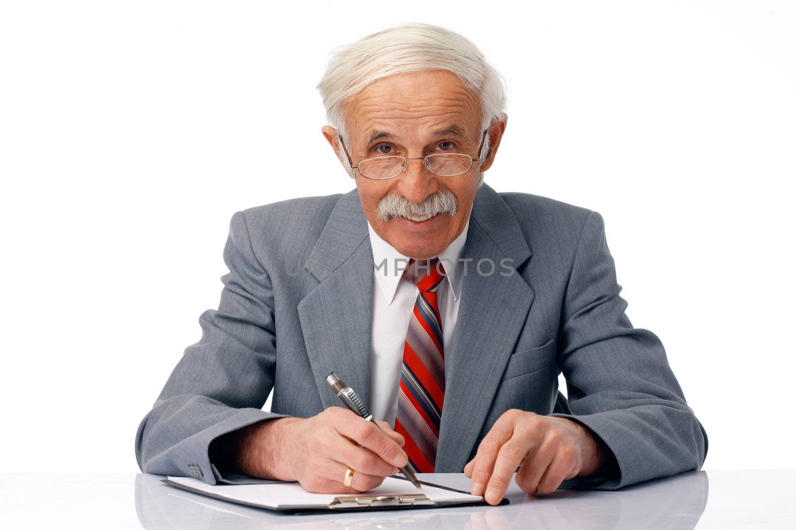 Portrait of an elder smiling man writing something and looking at you.