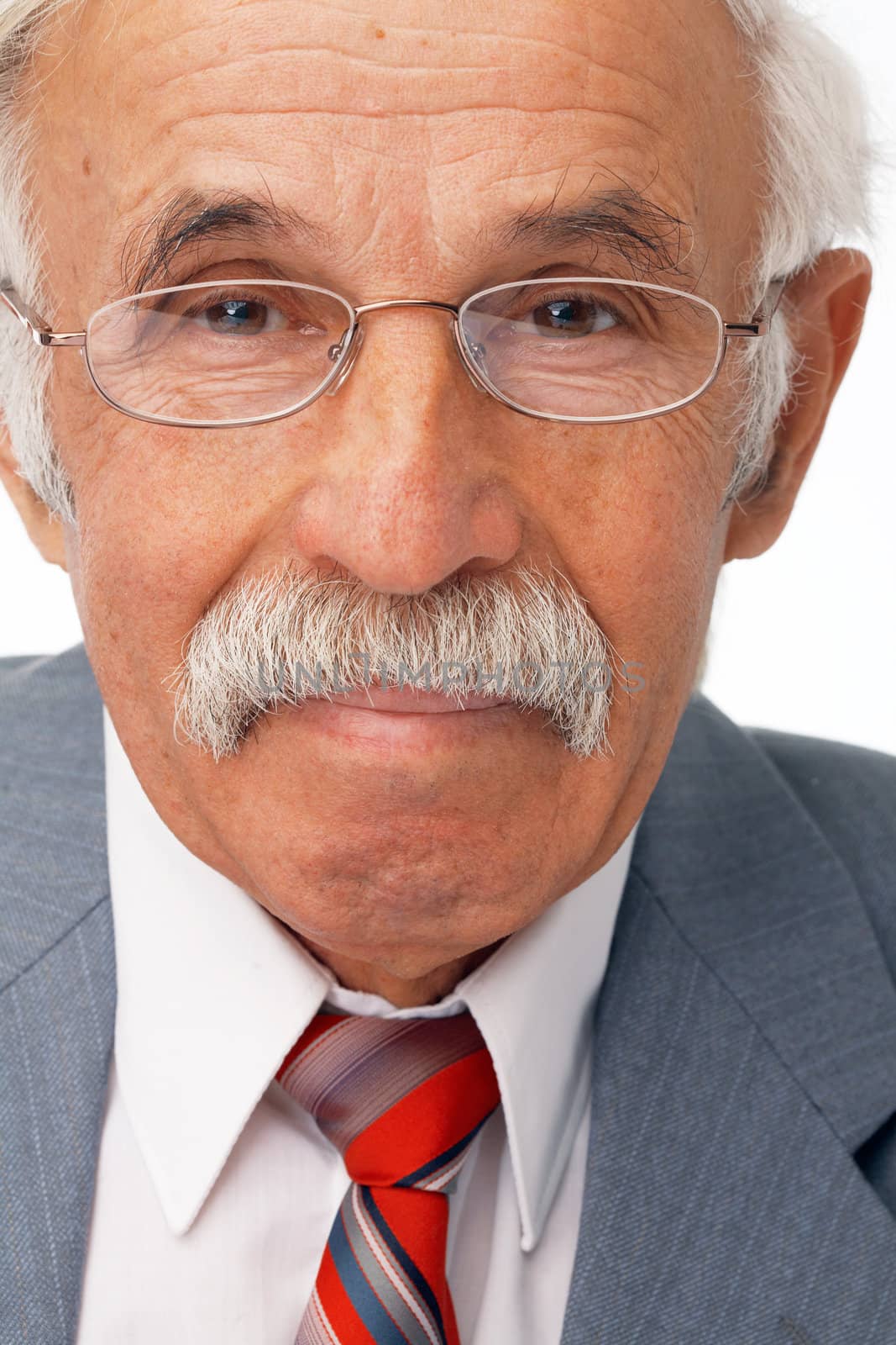 Close-up portrait of an elder businessman looking at you and smiling.