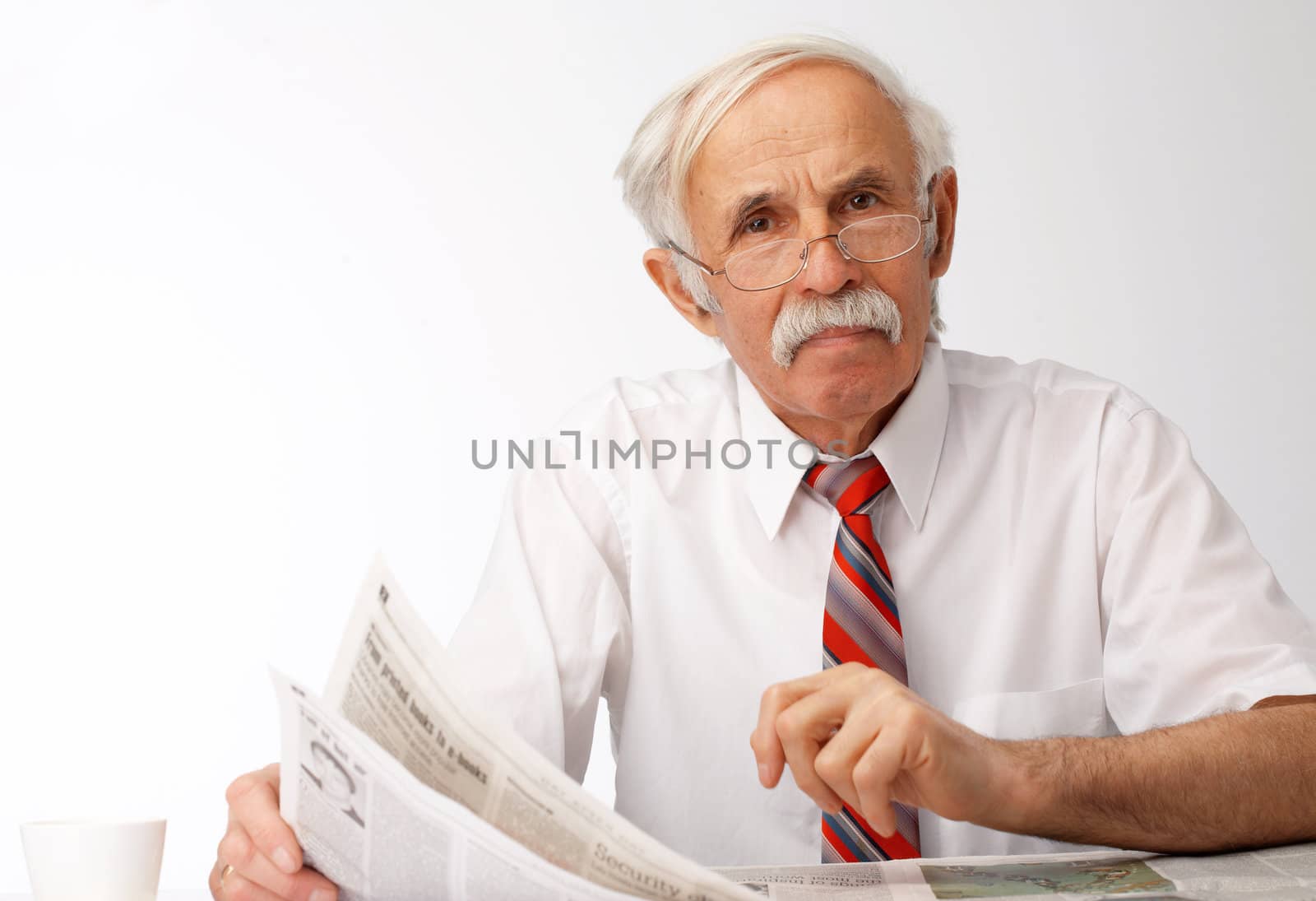 Portrait of an elder man holding an newspaper and looking at you.