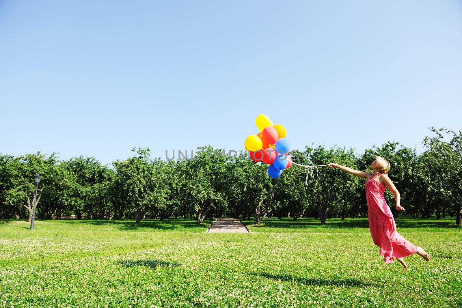 Girl jumping with balloons trying to fly