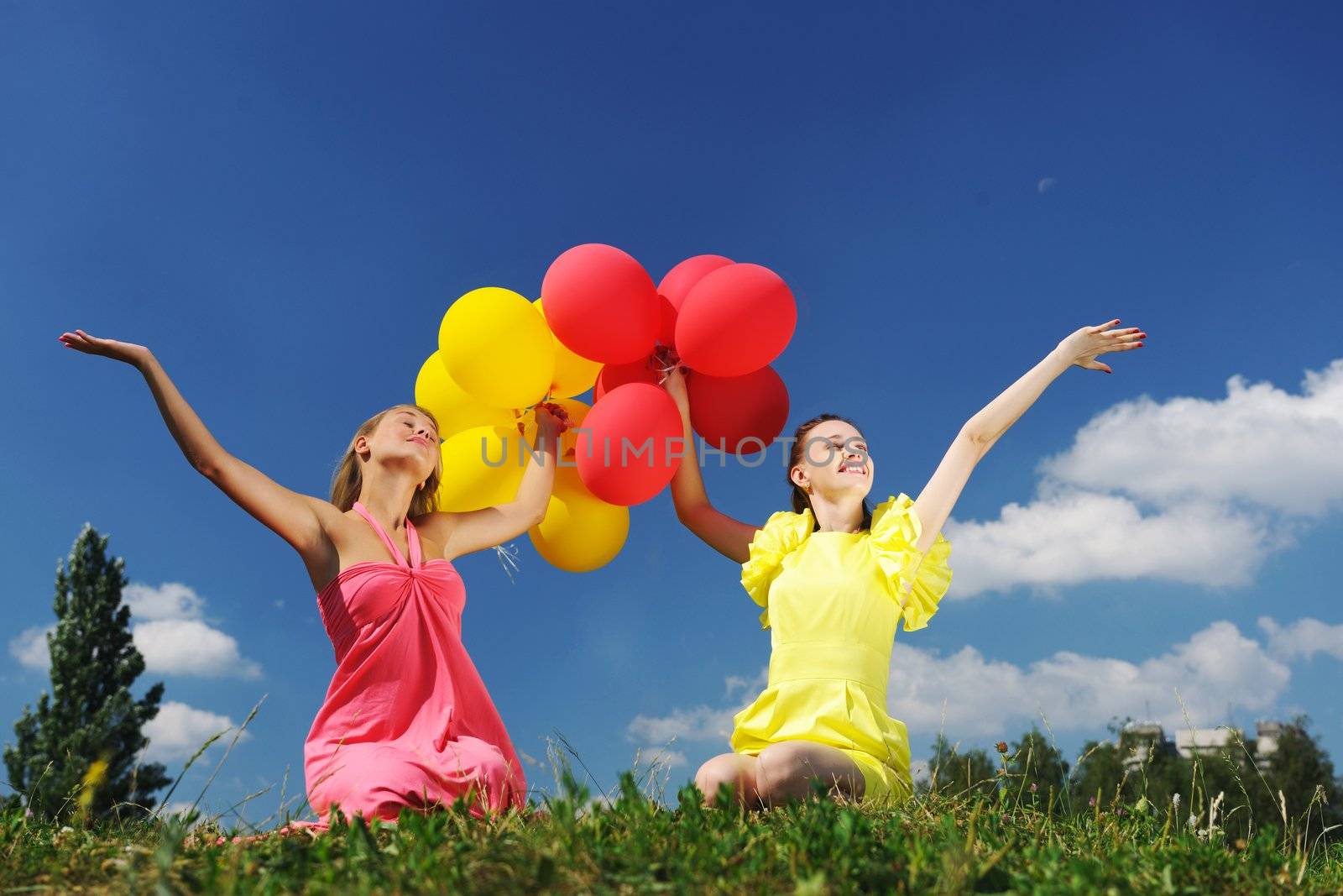 Girls holding balloons against sky