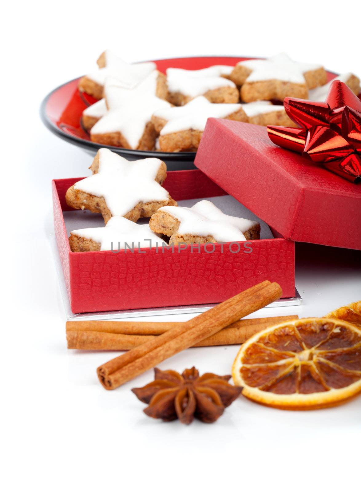 star shaped cinnamon biscuit in red box with Anise, cinnamon and orange on white background