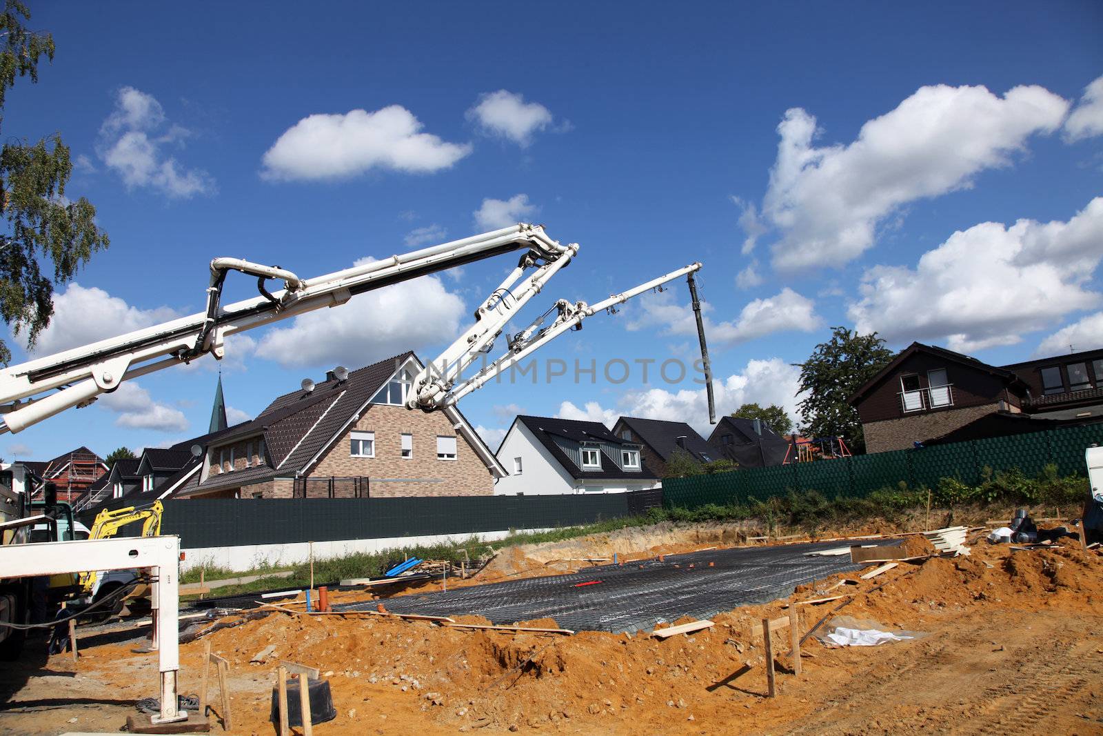View of a new house building site with a long mechanical arm and tube for pouring ready mixed concrete for the foundation and floor 