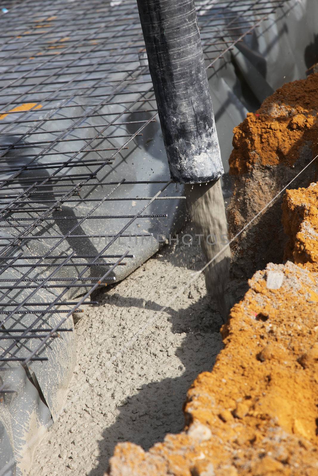 Pouring a mixture of cement and stone for the foundations of a new house using a tube suspended from a mechanical arm 