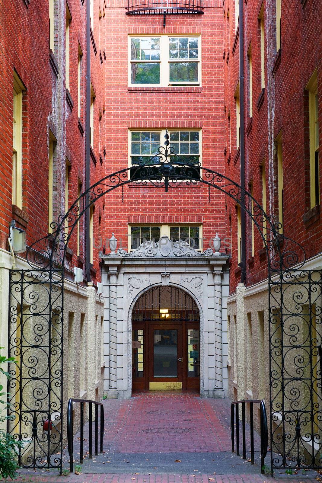 Hall leading to front door of an old brick apartment building with wrought iron entrance feature