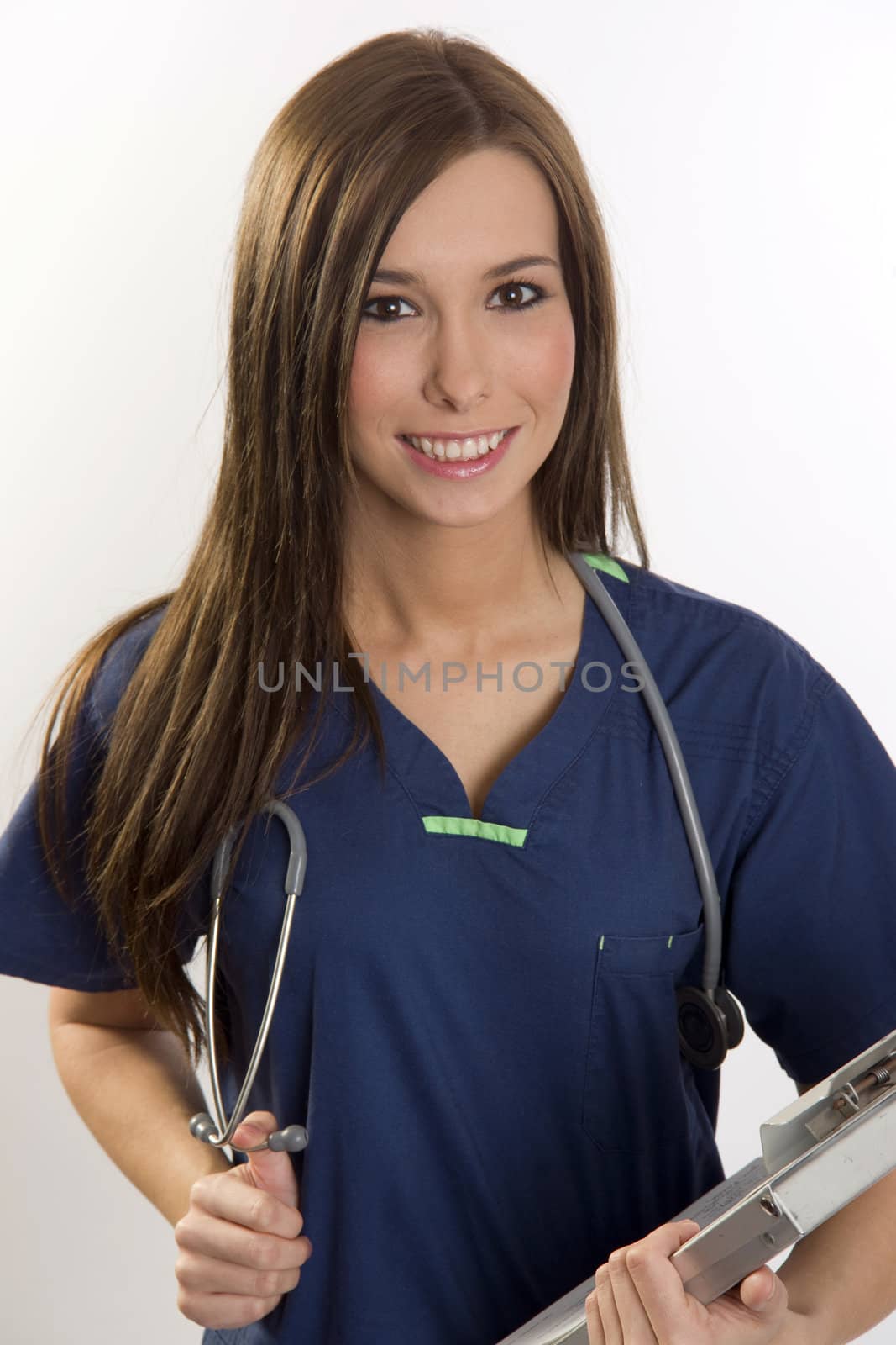 A beautiful health care worker looks up at the viewer carrying her clipboard