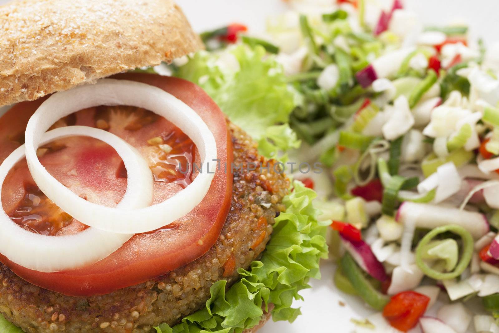Delicious and healthy quinoa burger topped with a tomato slice and onions
