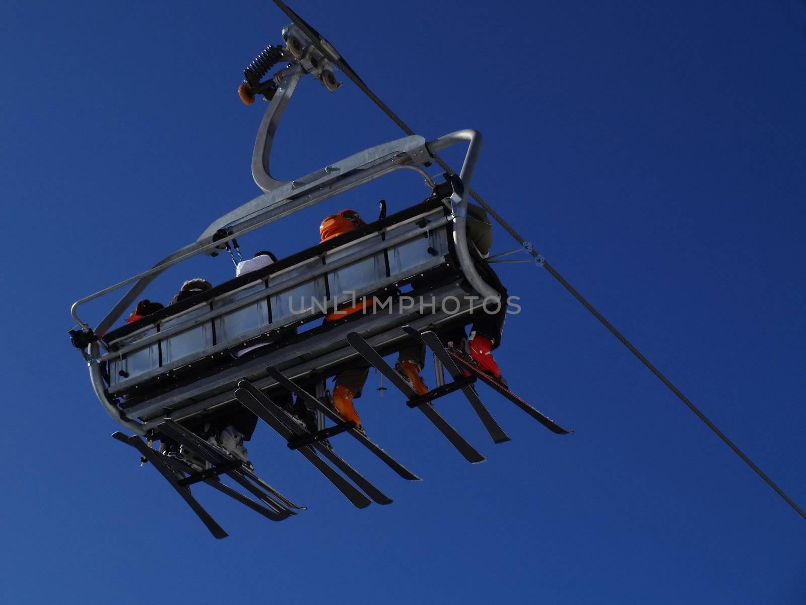 Ski lift carrying skiers. by anderm