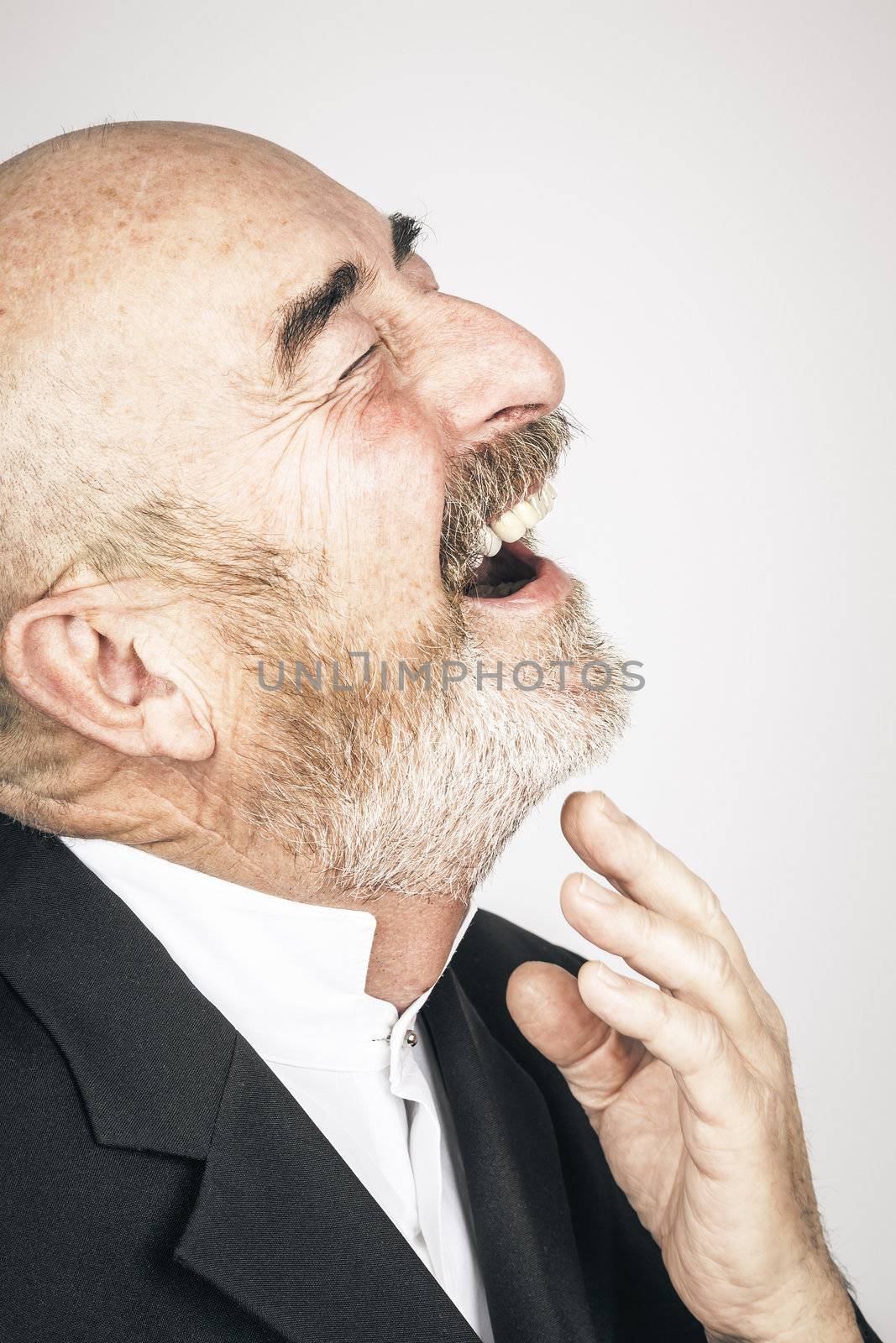 An old man with a grey beard is laughing