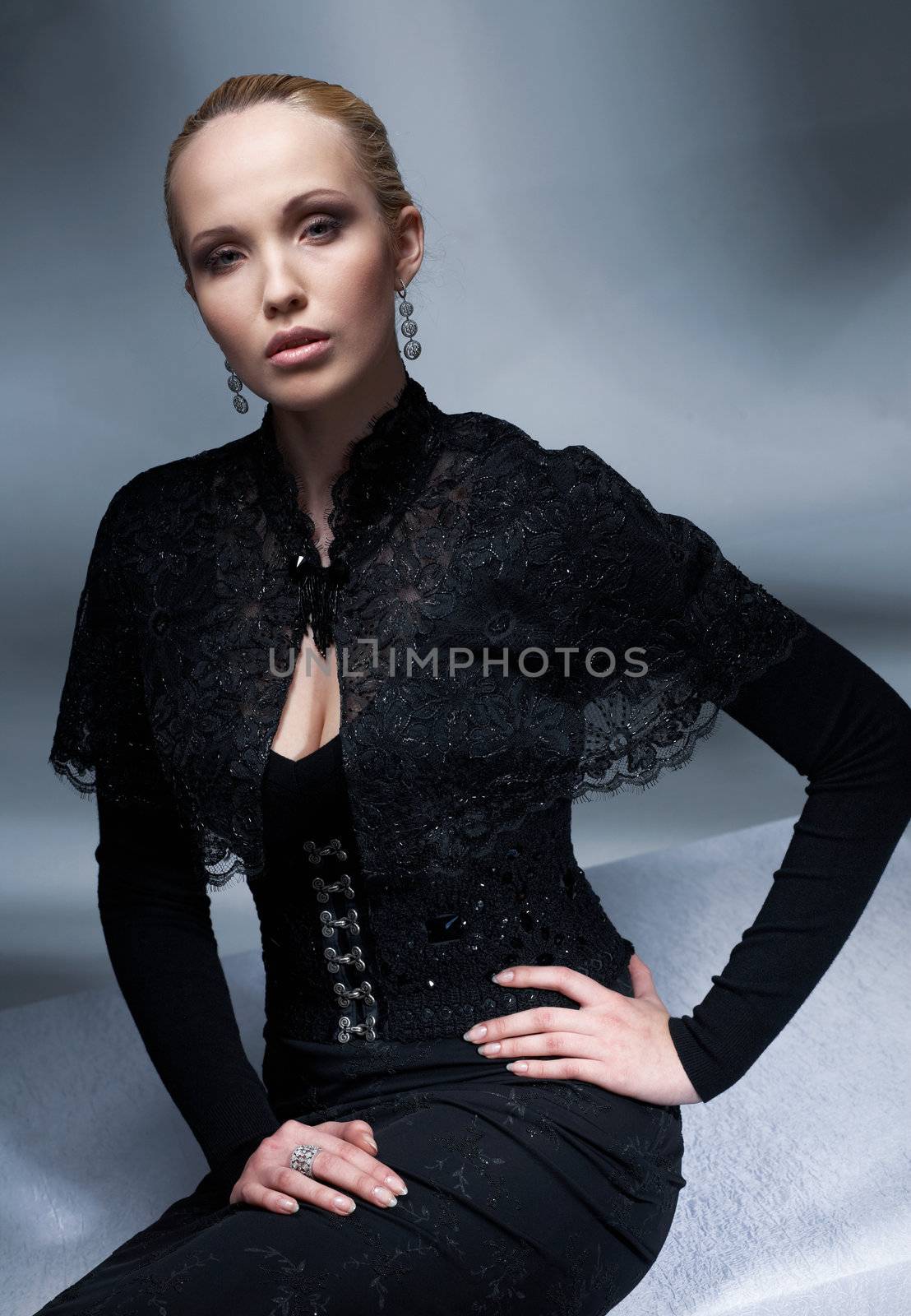 Beautiful blond model sitting and posing in the black vintage clothes.