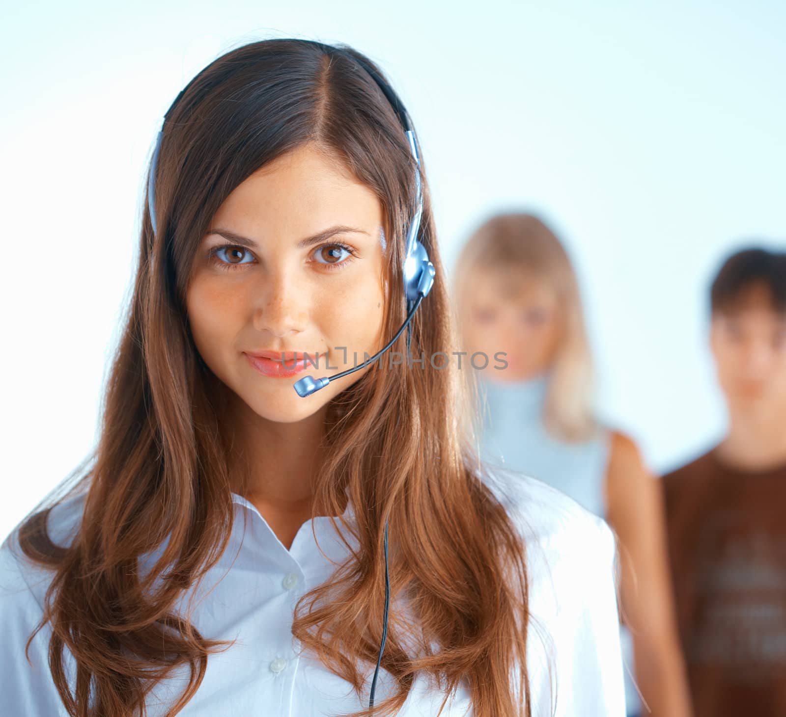 Young beautiful woman with headset with some people at the background
