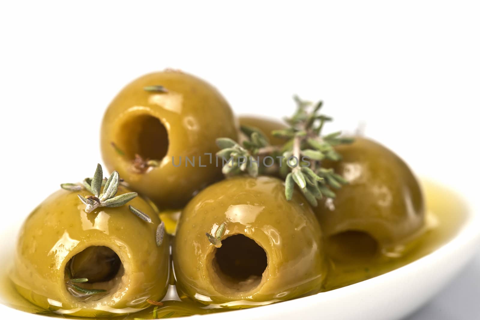 Pitted olives in a saucer isolated on a white background.