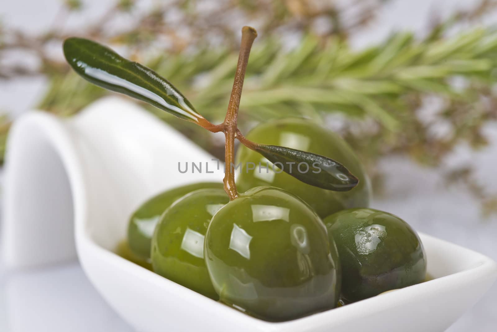 Green olives in a china spoon over a white background
